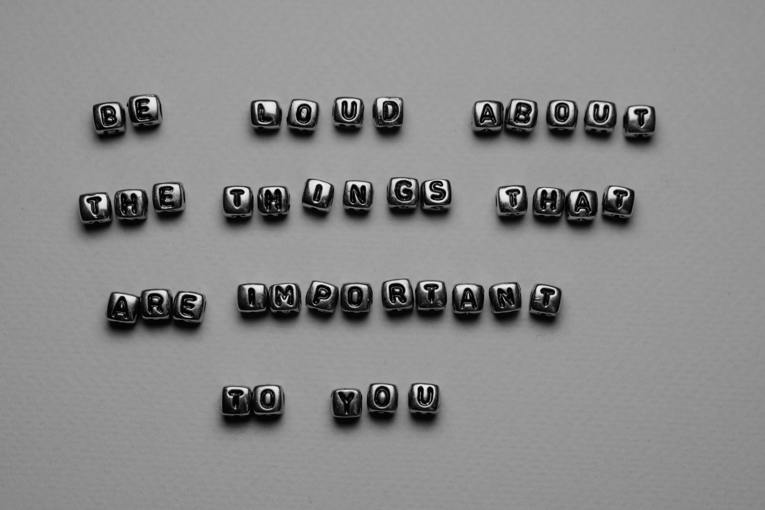 aajkitajikhabar .com Motivational message displayed with alphabet cube beads on a monochrome background.
