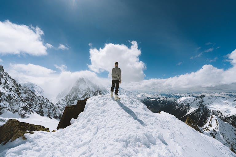 Jant Blanc Person standing on a snow-covered peak in Chamonix-Mont-Blanc, France, showcasing a breathtaking mountain view.
