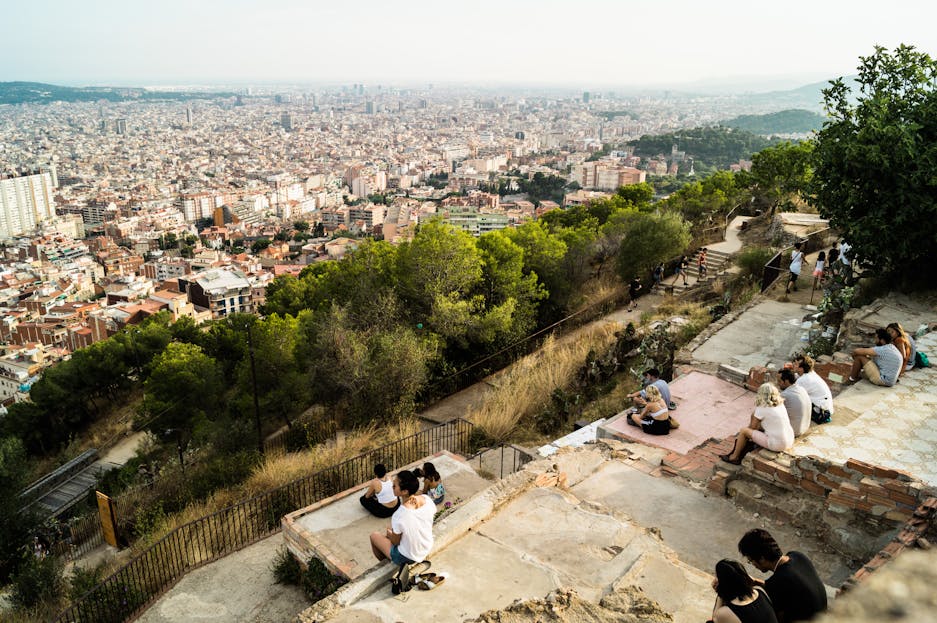Carmela Clouth Relaxed tourists enjoy a panoramic view of Barcelona's skyline from Bunkers del Carmel.