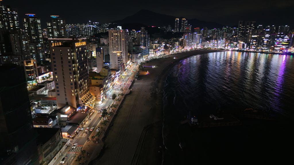 The Vzusa Stunning night view of Busan's skyline and beach, showcasing vibrant city lights.