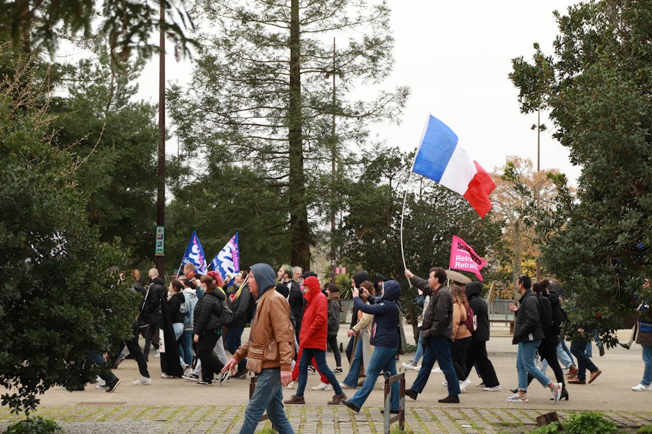 IPLLeague2026 A group of people marching outdoors in a protest holding French flags, showcasing unity and movement.