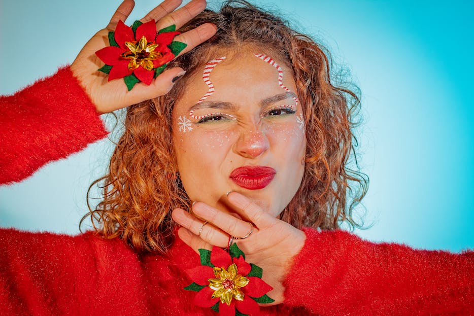 Twastia.com.au Cheerful woman in red sweater posing with festive poinsettia-themed makeup for the holiday season.