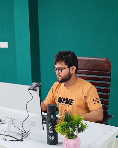 Kongotech Focused young man in modern office setting working on computer, emphasizing productivity and technology.