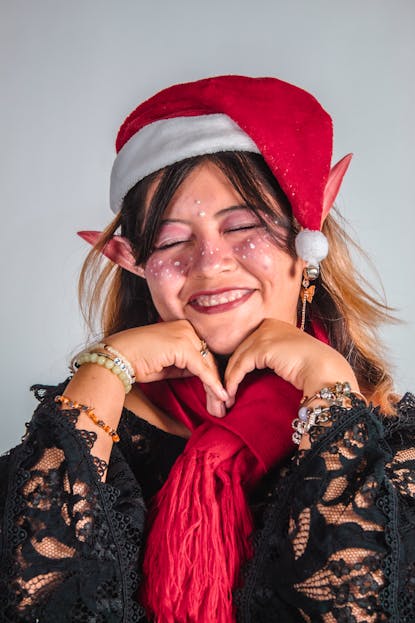 Twastia.com Team Members Happy woman with elf ears and Santa hat celebrates Christmas cheerfully.