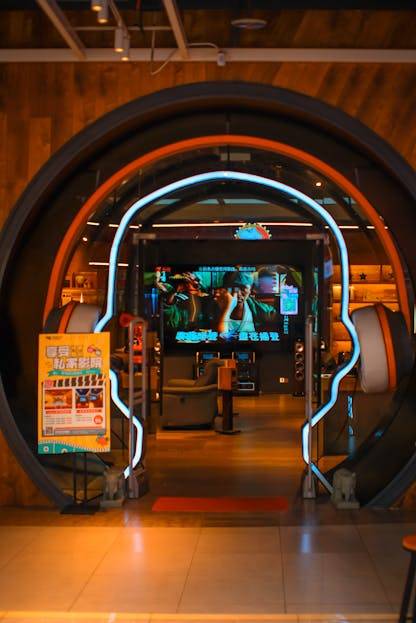 Stylish store entrance featuring a headphone design with bright neon lights and electronics in the background.