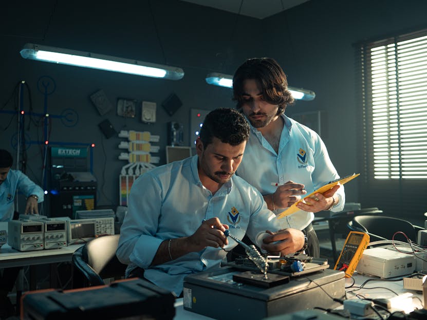 Kongotech Two men working on an electronics project in a Baghdad lab, focused and collaborating.