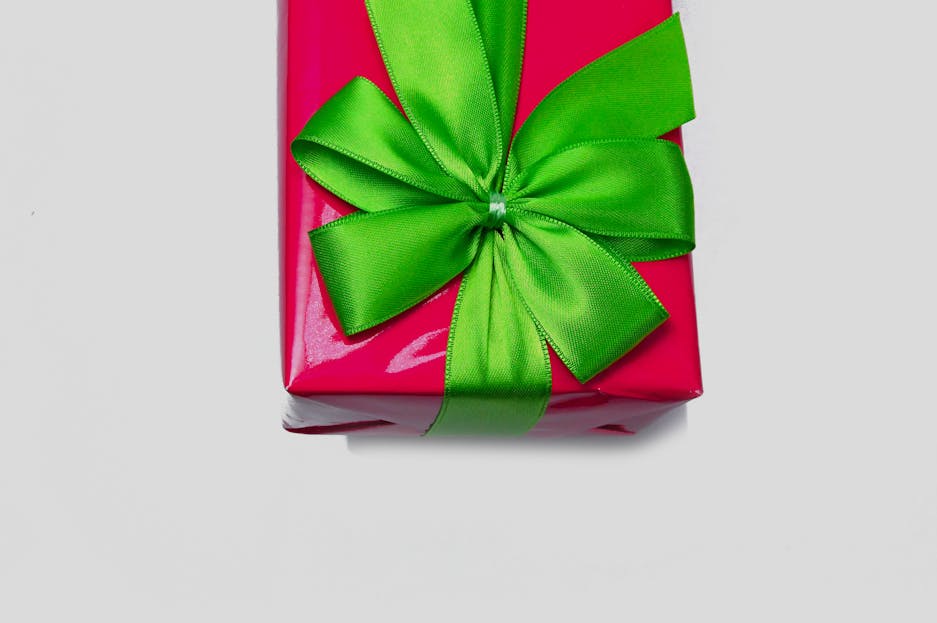 WhatUTalkingBoutWillis Gifts A bright red gift wrapped in a glossy paper with an elegant green ribbon bow.