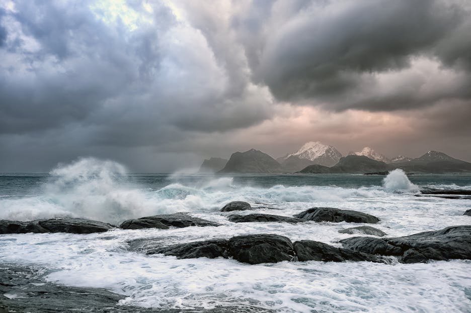 Stormuring A dramatic view of the stormy coastline in Nordland, Norway with waves crashing on rocks under cloudy skies.
