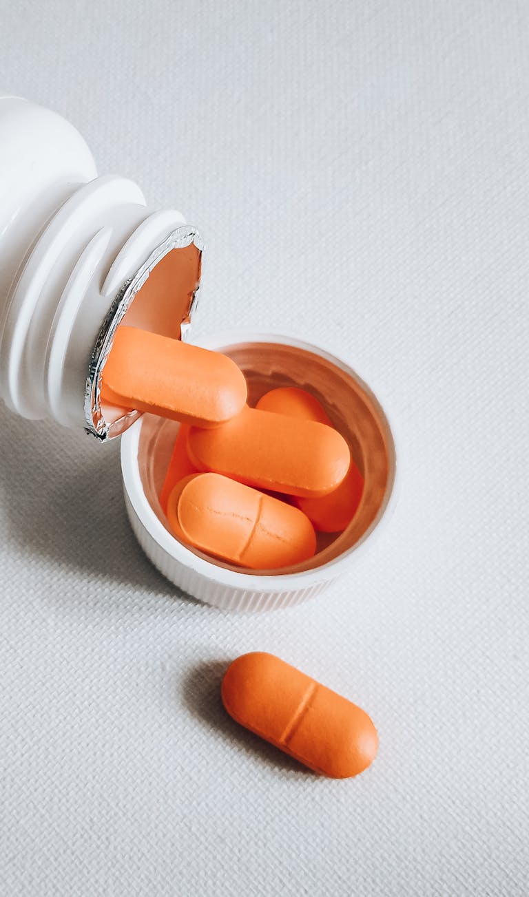 CenturyLinkOnline.com Close-up of orange pills spilling from a white bottle on a textured surface.