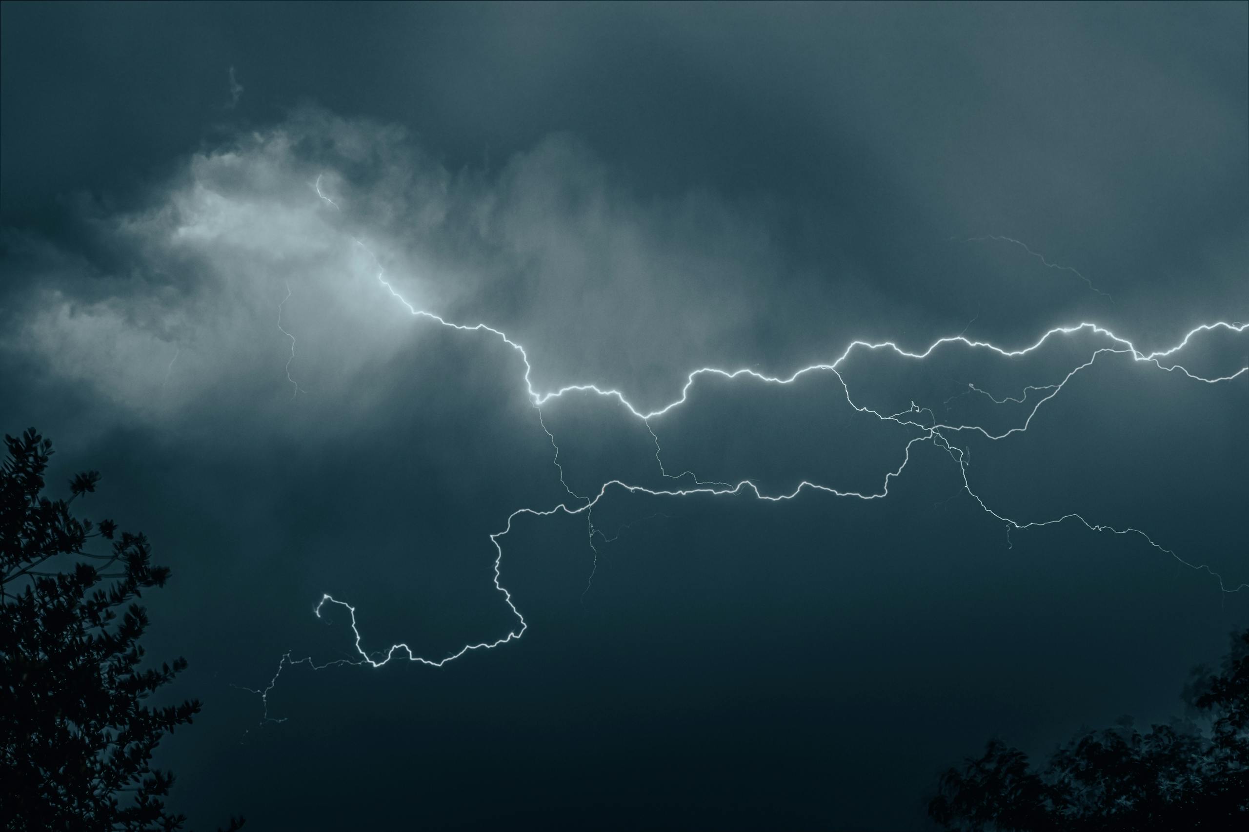 Petir108win.online Powerful lightning bolt cutting through a moody, dark sky during a thunderstorm.