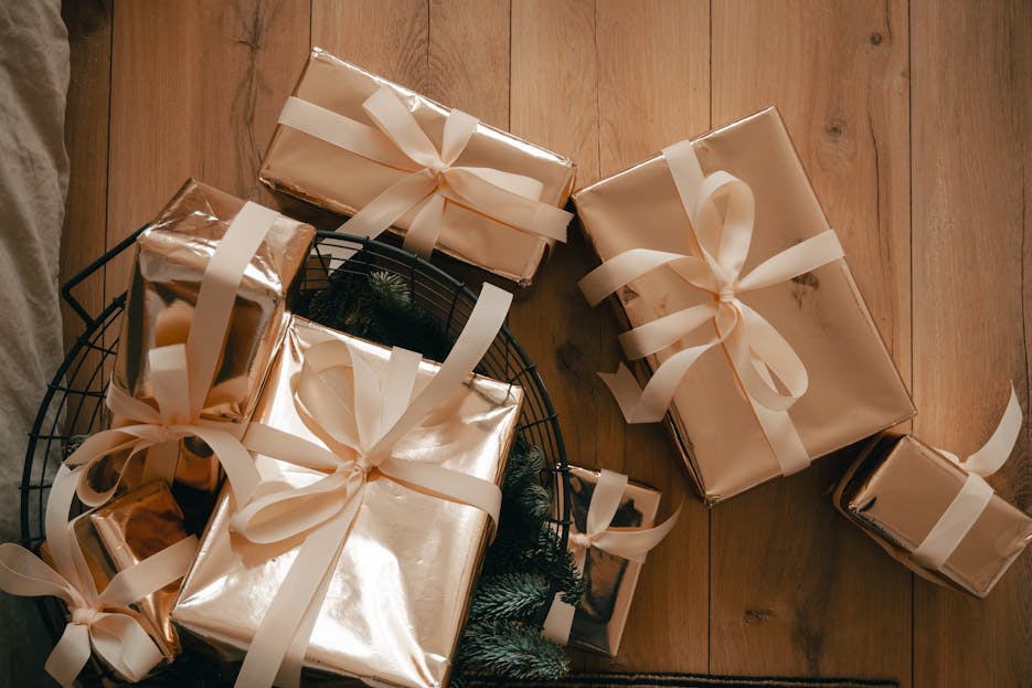 WhatUTalkingBoutWillis Gift Guide Top view of elegantly wrapped gift boxes with ribbons on wooden floor, perfect for holiday imagery.