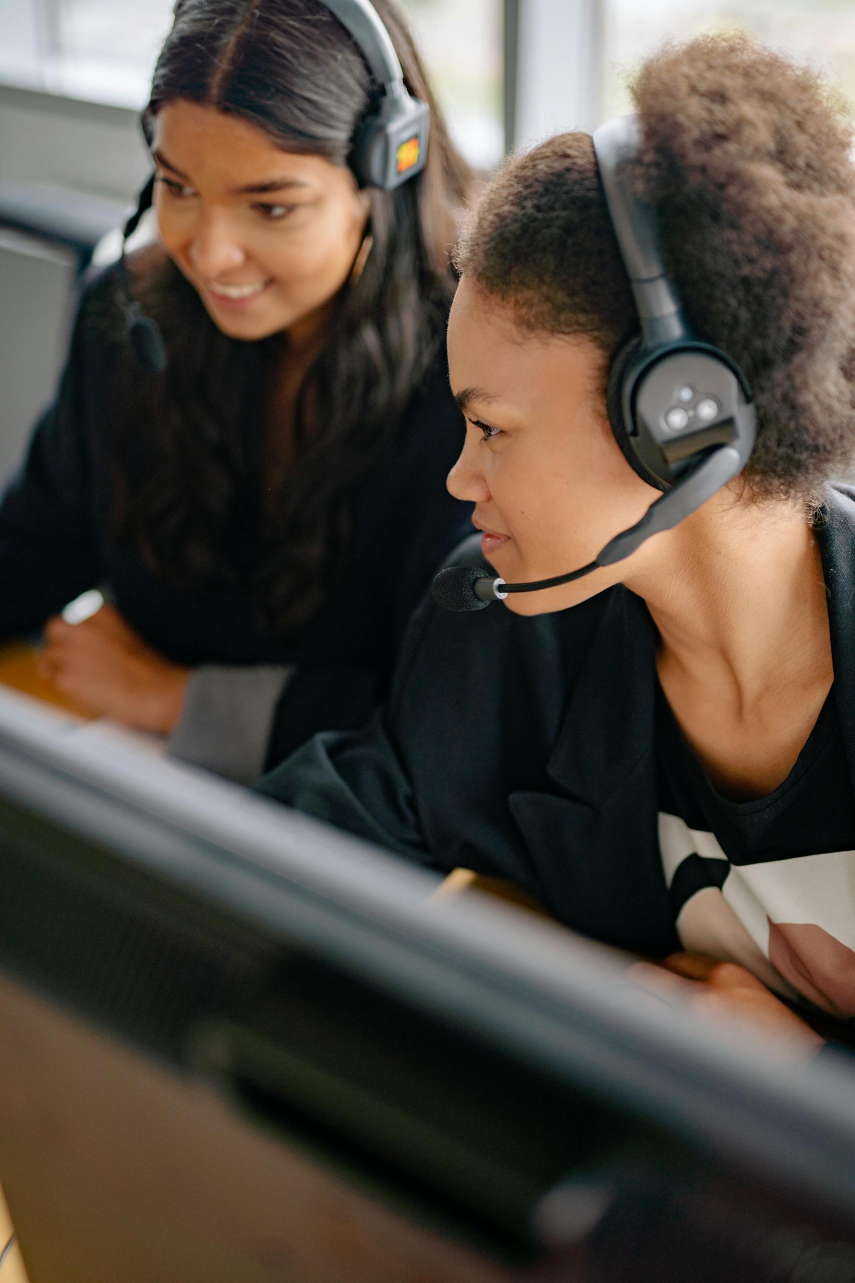 Century LinkT wo diverse women working as call center agents in an office setting.